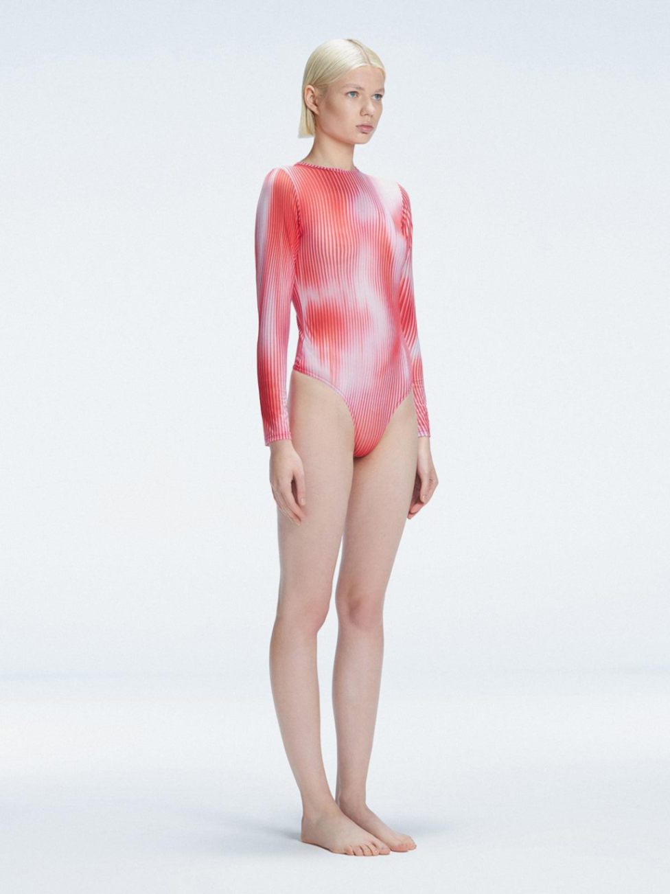 Side view of model showcasing the intricate mesh fabric and optical pattern on the Mireya Red  Bodysuit.
