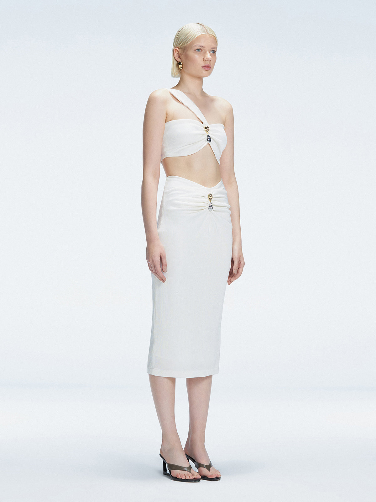 Side view of model showcasing the ruched front and sleek silhouette of the Esmeralda WhiteMidi Skirt.
