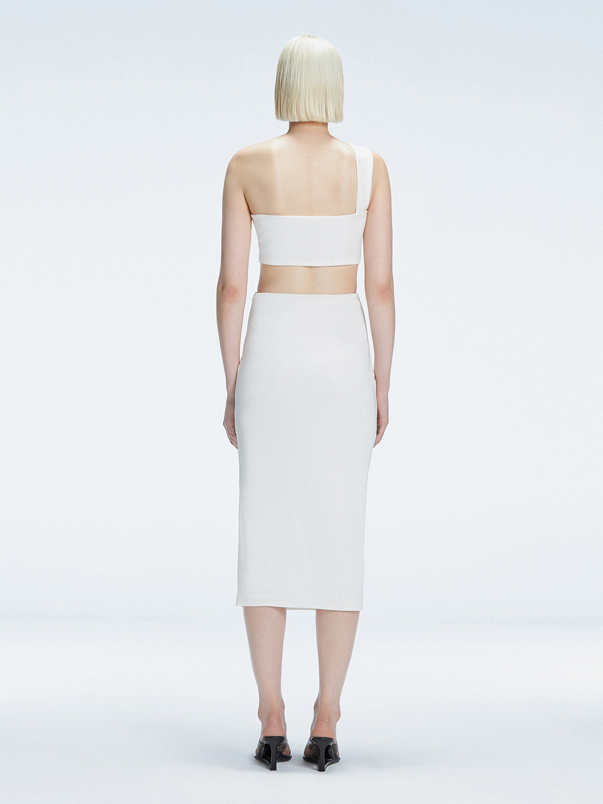 Back view of model wearing Esmeralda White Midi Skirt, highlighting the seamless hidden zipper.
