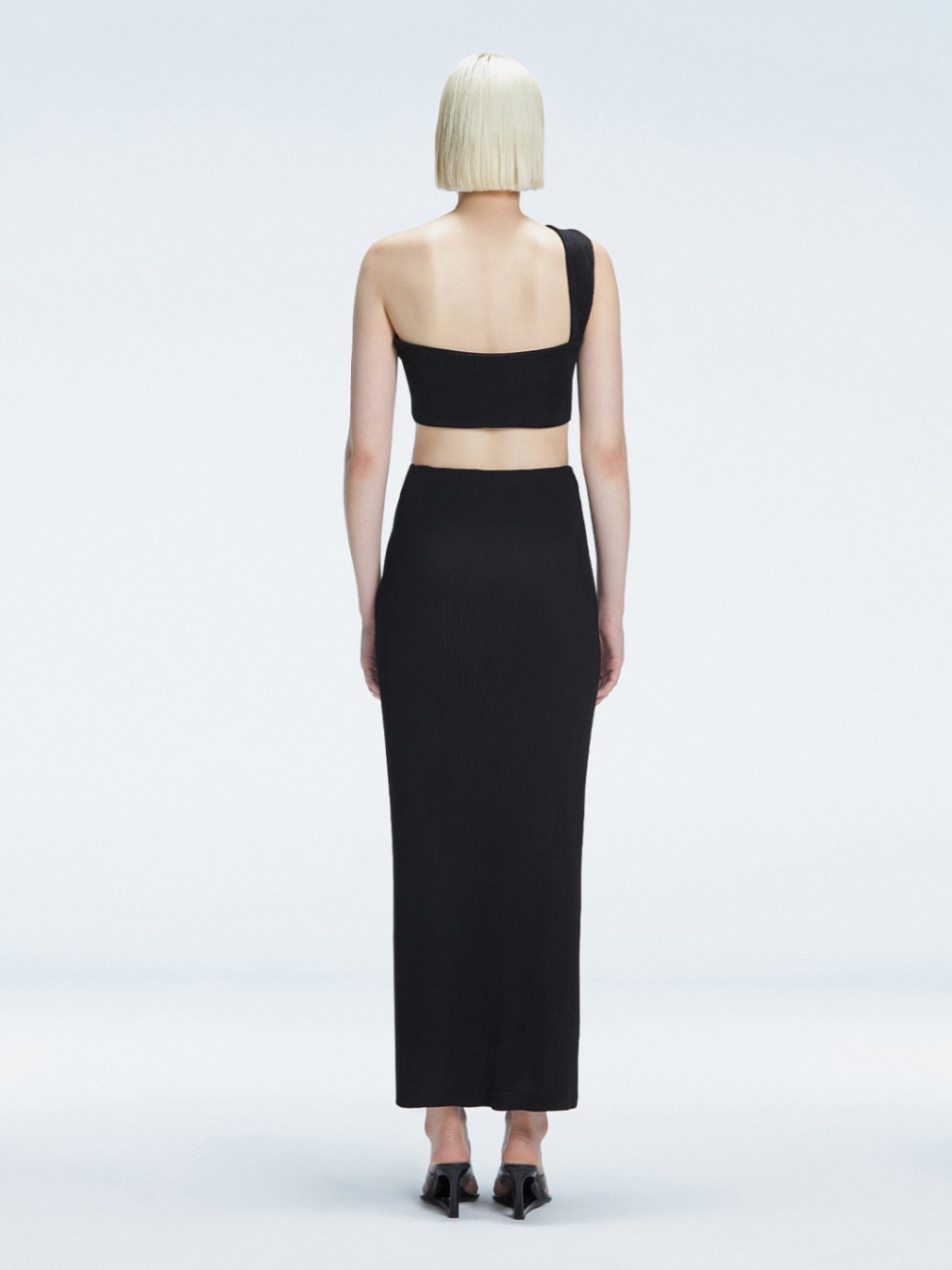 Back view of model wearing Lane Black Top, highlighting the sleek one-shoulder silhouette.
