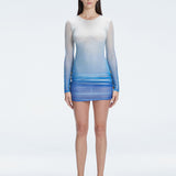 Model showcasing the Sylvie Blue Sonar Dress, highlighting its elegant long sleeves and draped skirt