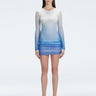 Model showcasing the Sylvie Blue Sonar Dress, highlighting its elegant long sleeves and draped skirt