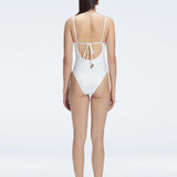 "Model showing the back of the Emma White Swimsuit, highlighting the sleek fit and moderate coverage."
