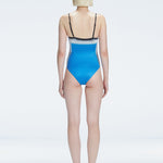 Back view of model wearing Camilla BlueOptical Swimsuit, highlighting the sleek fit and moderate coverage.
