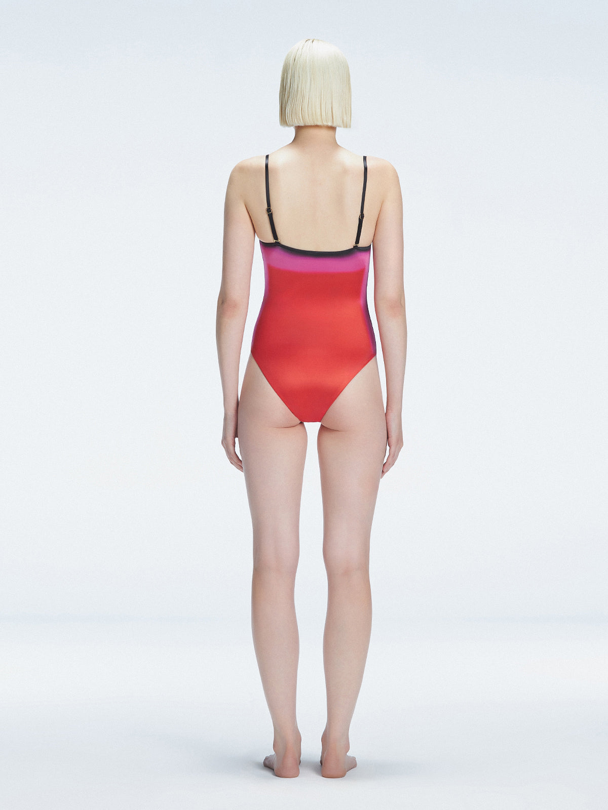 Back view of model wearing Camilla Pink Optical Swimsuit, highlighting the sleek fit and moderate coverage.
