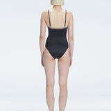 Back view of model wearing Camilla Black Optical Swimsuit, highlighting the sleek fit and moderate coverage.
