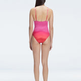 Back view of model wearing Marina Degraded Red-Pink One Piece swimsuit, featuring accessory details on straps and open back design.
