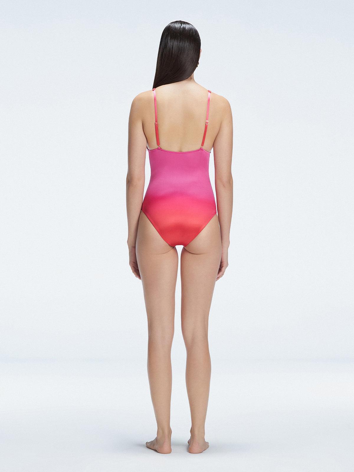 Back view of model wearing Marina Degraded Red-Pink One Piece swimsuit, featuring accessory details on straps and open back design.
