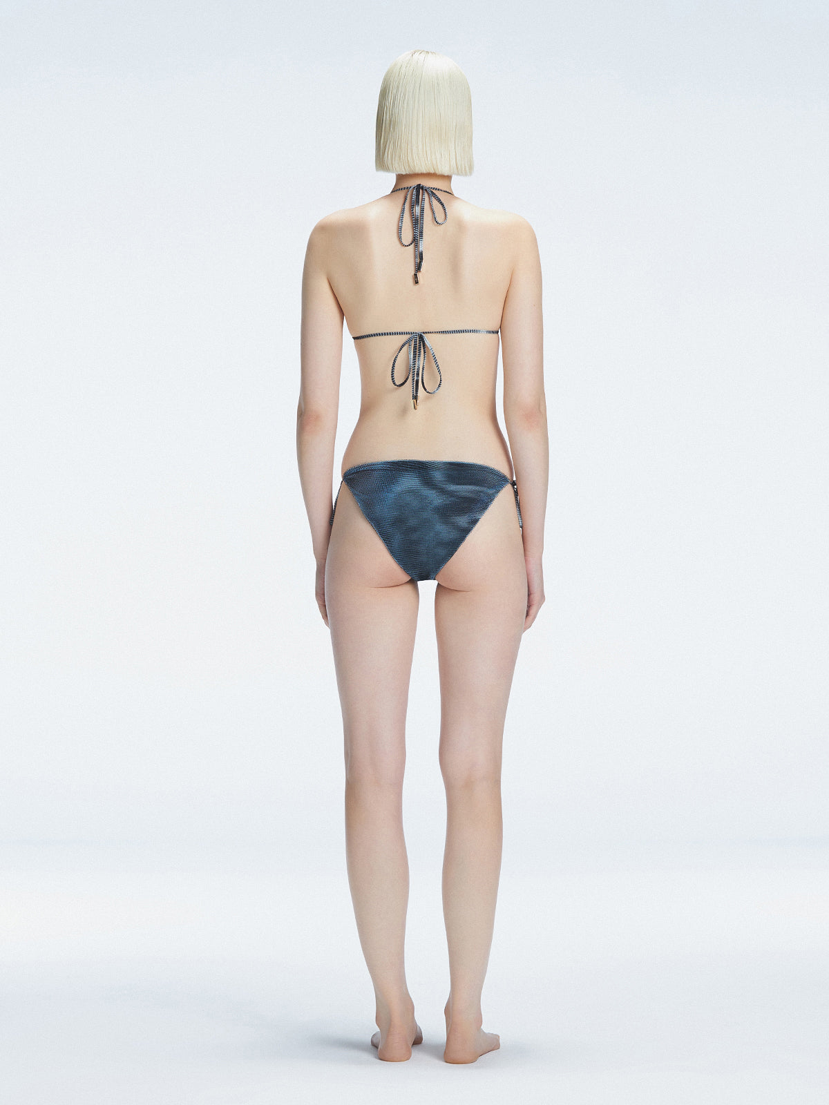 Back view of model wearing Hermione Black Optical Bikini Top, highlighting the adjustable back ties and sleek fit.
