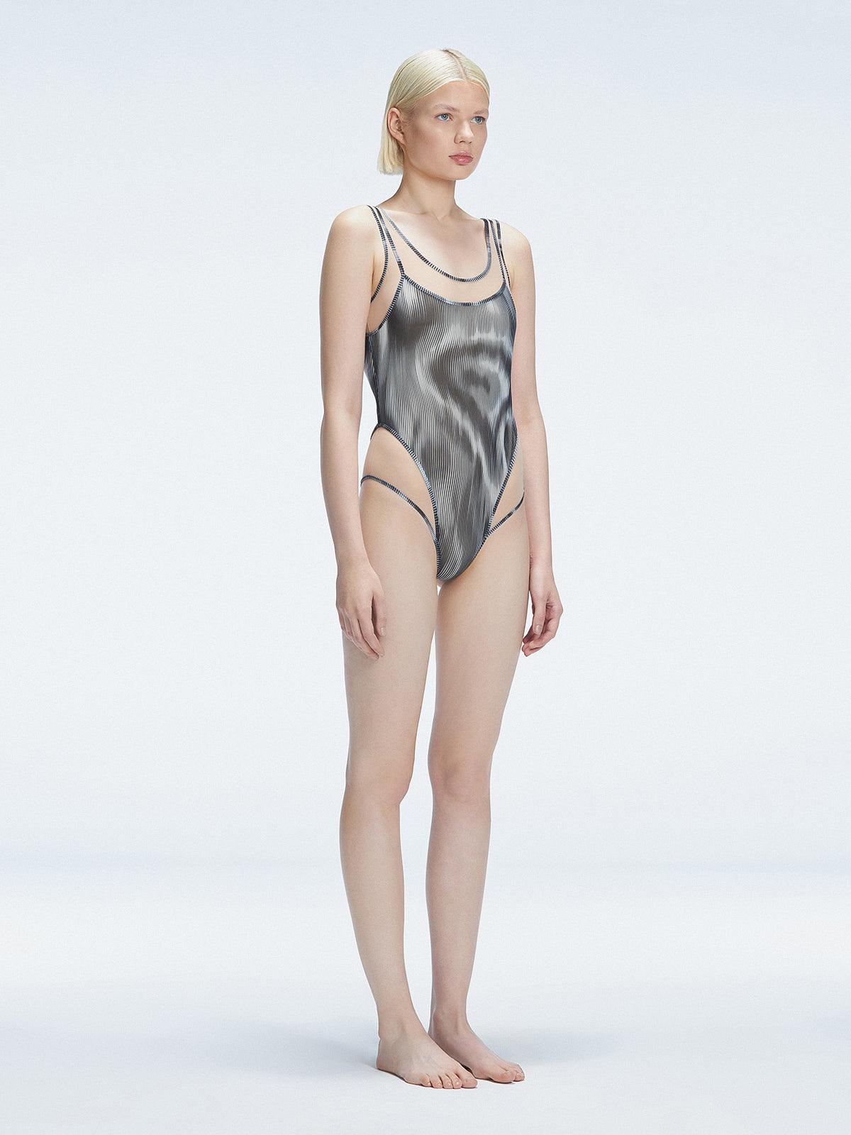 Side view of model showcasing the printed tulle and scoop neck on the Calista Black Swimsuit.
