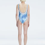 Back view of model wearing Calista Blue Optical Swimsuit, highlighting the sleek fit and moderate bottom coverage.
