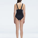 Back view of model in Griselda Black One Piece swimsuit, featuring moderate bottom coverage and ruched straps.
