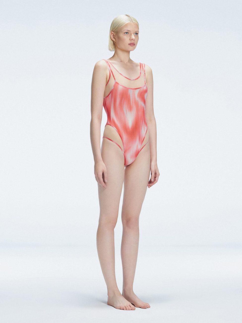 Side view of model showcasing the printed tulle and scoop neck on the Calista Red Swimsuit.
