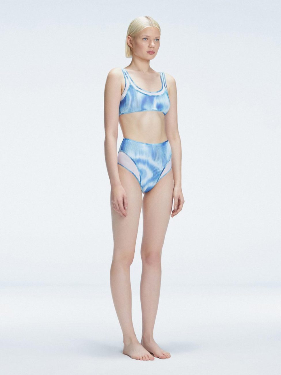 Side view of model showcasing the printed tulle and sleek high-waist fit on the Rosalind Blue Bikini Set.
