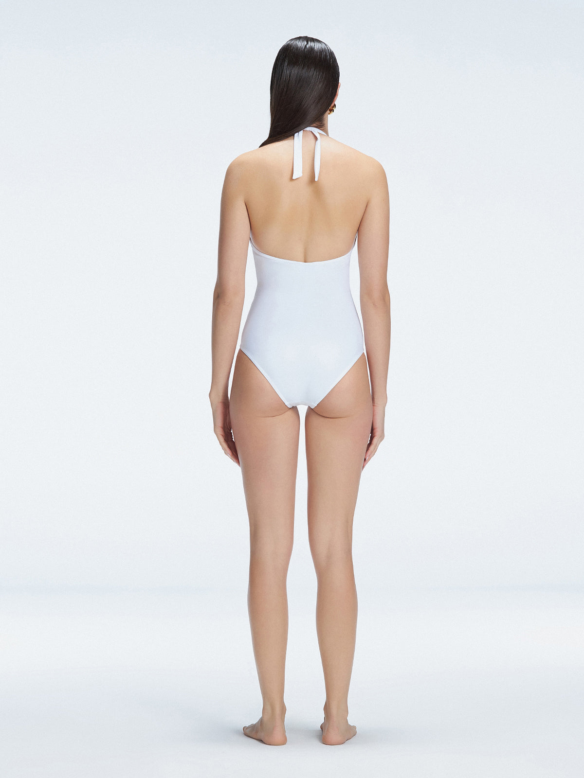 Back view of model wearing Miley White One Piece swimsuit, highlighting the tie closure and full bottom coverage.
