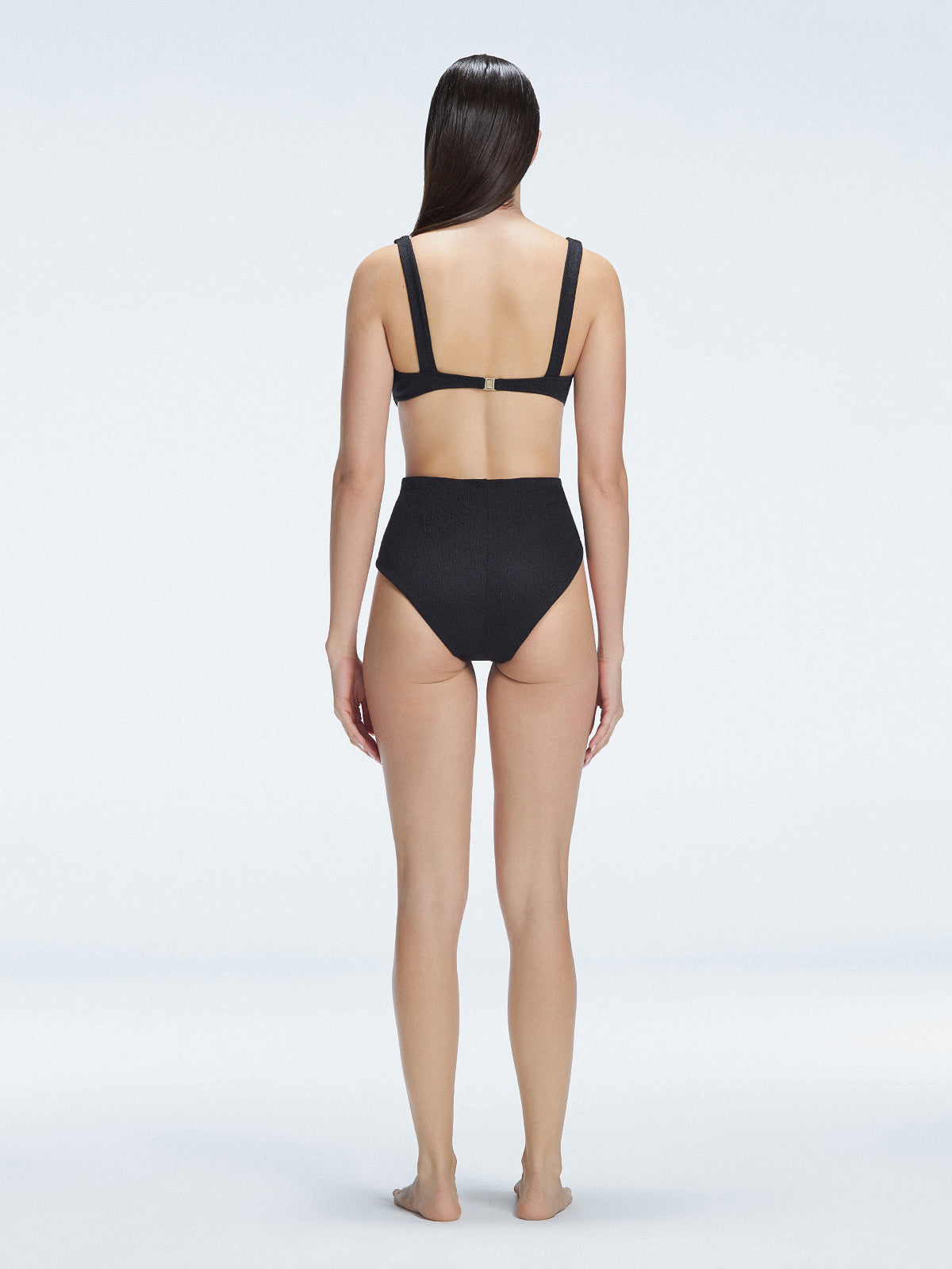 "Model showcasing the back of the Madelyn Black Bikini Top and Dylan Bikini Bottom, highlighting the secure gold clasp fastening."
