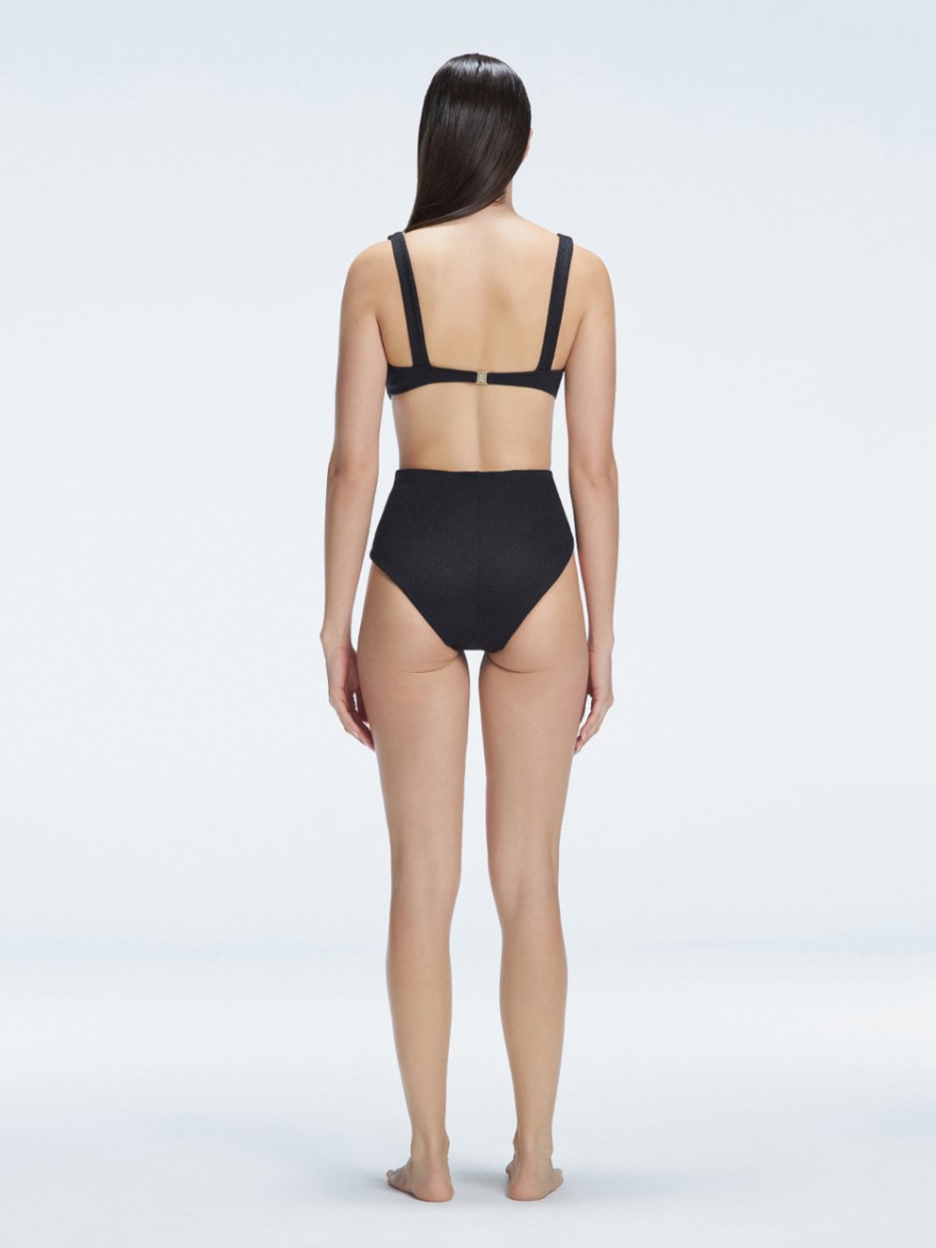 "Model showcasing the back of the Dylan Black Bikini Bottom, emphasizing the comfortable fit and moderate coverage."
