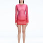 Model showcasing the Sylvie Pink Sonar Dress, highlighting its elegant long sleeves and draped skirt