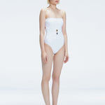 Side view of model showcasing the strapless design and gold accent on the Ursula White One Piece swimsuit.
