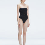 Side view of model showcasing the strapless design and gold accent on the Ursula Black One Piece swimsuit.
