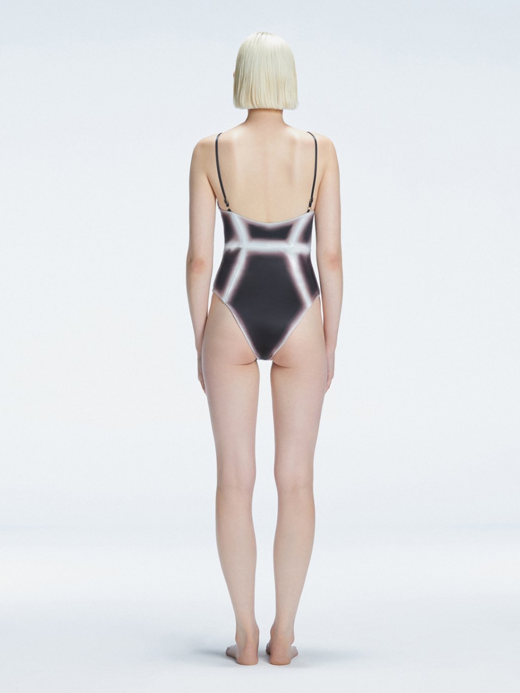 Back view of model wearing Seraphina  Black Optical One Piece, highlighting the sleek fit and moderate coverage.
