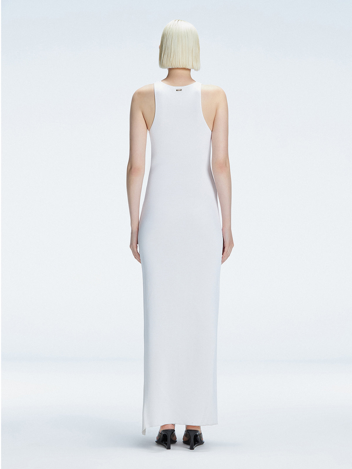 Back view of model wearing Louisa White Maxi Dress, highlighting the high neck and sleek silhouette.
