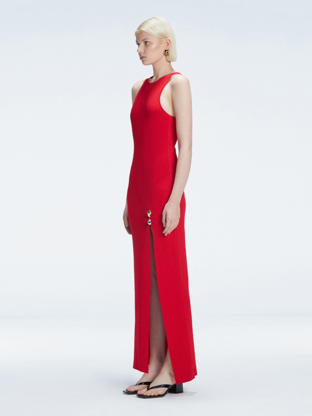 Side view of model showcasing the deep slit and chic buckle on the Louisa Red Knitwear Maxi Dress.
