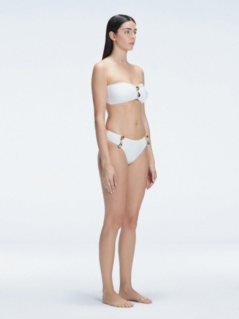 "Model in the Ilana White Bikini Set viewed from the side, highlighting the stylish buckle detail and ruched accents."


