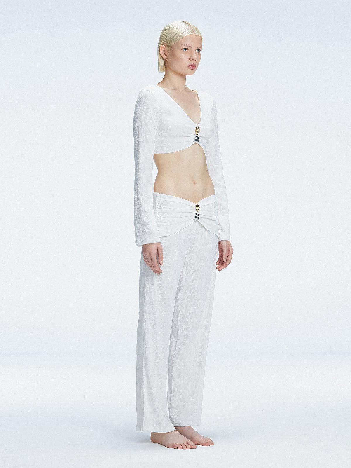 Side view of model showcasing the ruched front and buckle detail on the Sirenia White Crop Top.
