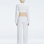 Back view of model wearing Sirenia White Crop Top and Helena Pants, highlighting the mid-rise V-shaped waistline and wide-leg design.
