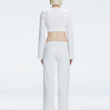 Back view of model wearing Sirenia White Crop Top and Helena Pants, highlighting the mid-rise V-shaped waistline and wide-leg design.
