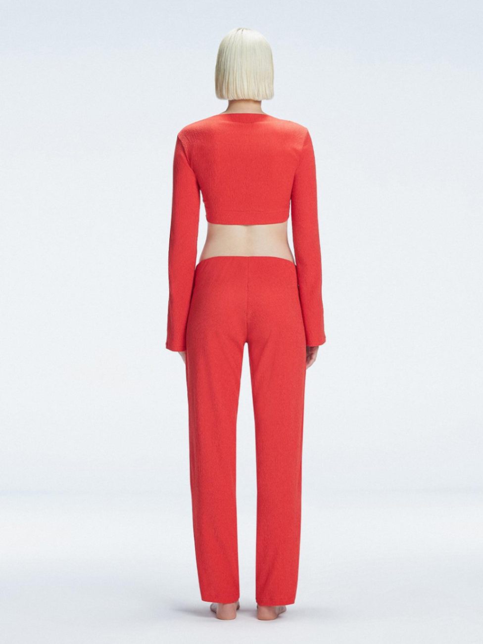 Back view of model wearing  Sirenia Red Crop Top and Helena Pants , highlighting the sleek silhouette and long sleeves.
