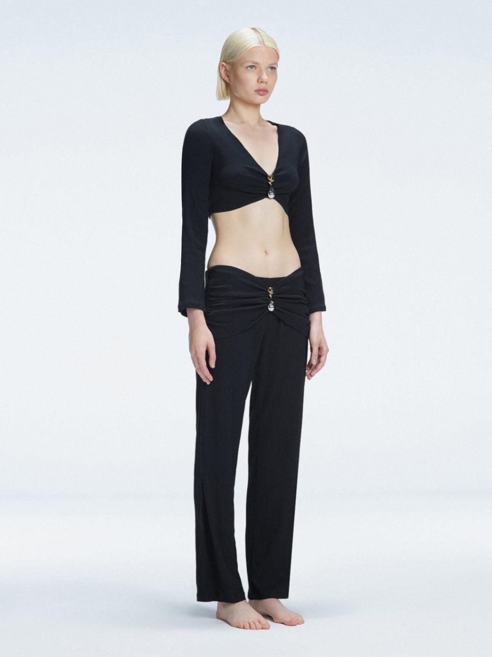 Side view of model showcasing the ruched front and buckle detail on the Sirenia Black Crop Top and Helena Pants 
