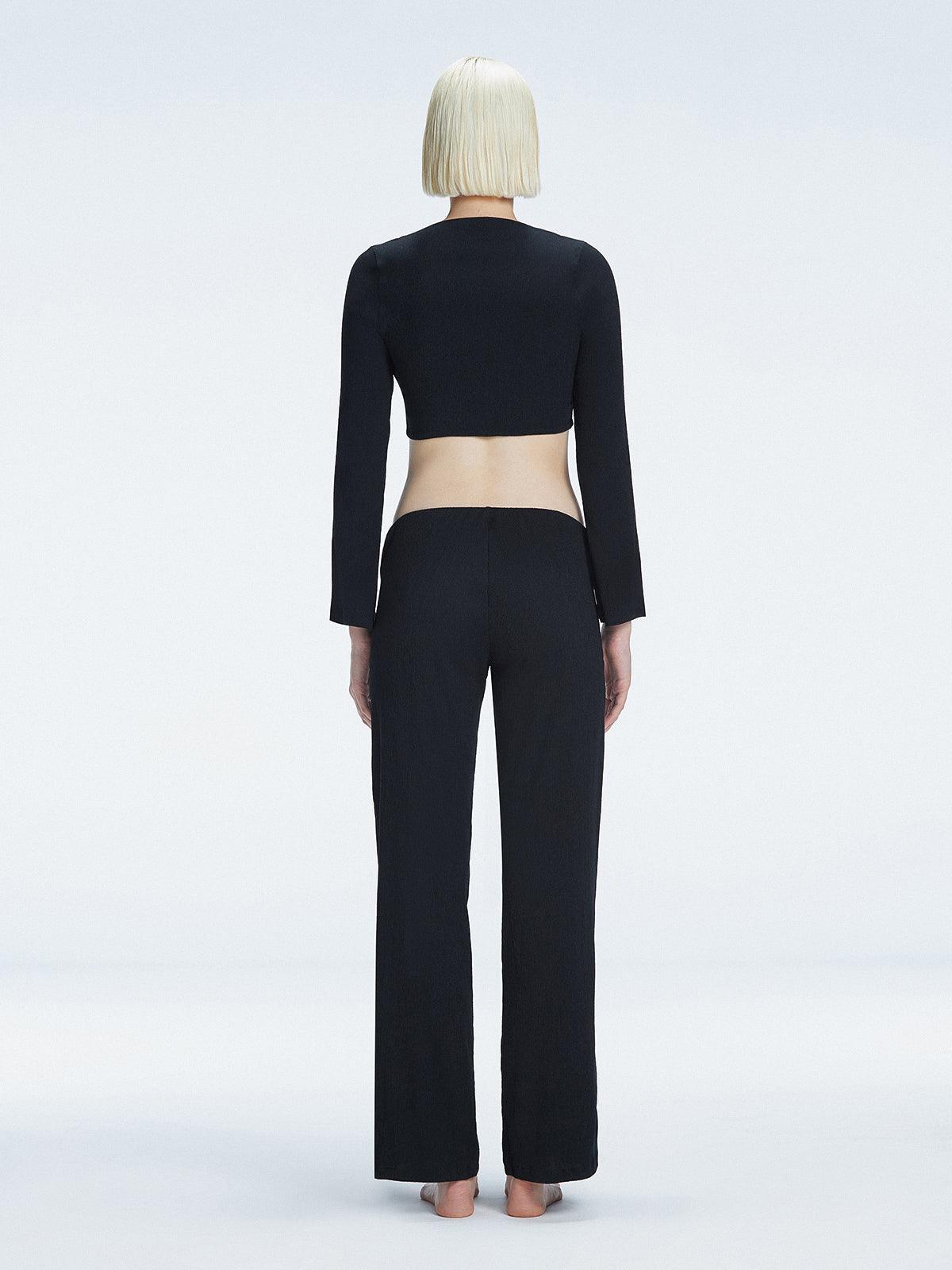 Back view of model wearing Sirenia Black Crop Top and Helena Pants , highlighting the sleek silhouette and long sleeves.
