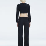 Back view of model wearing Helena Black Pants, highlighting the mid-rise V-shaped waistline and wide-leg design.
