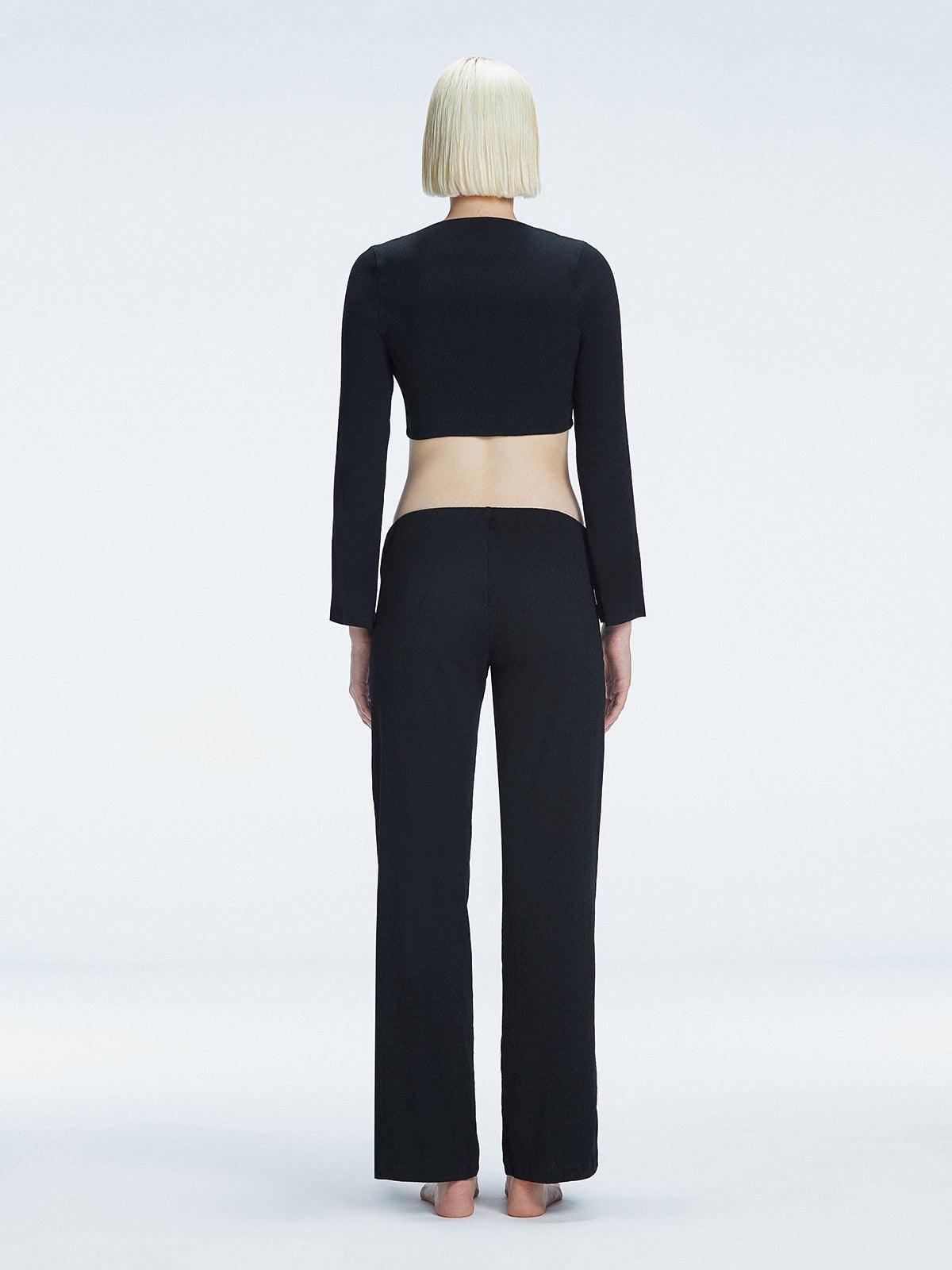 Back view of model wearing Helena Black Pants, highlighting the mid-rise V-shaped waistline and wide-leg design.
