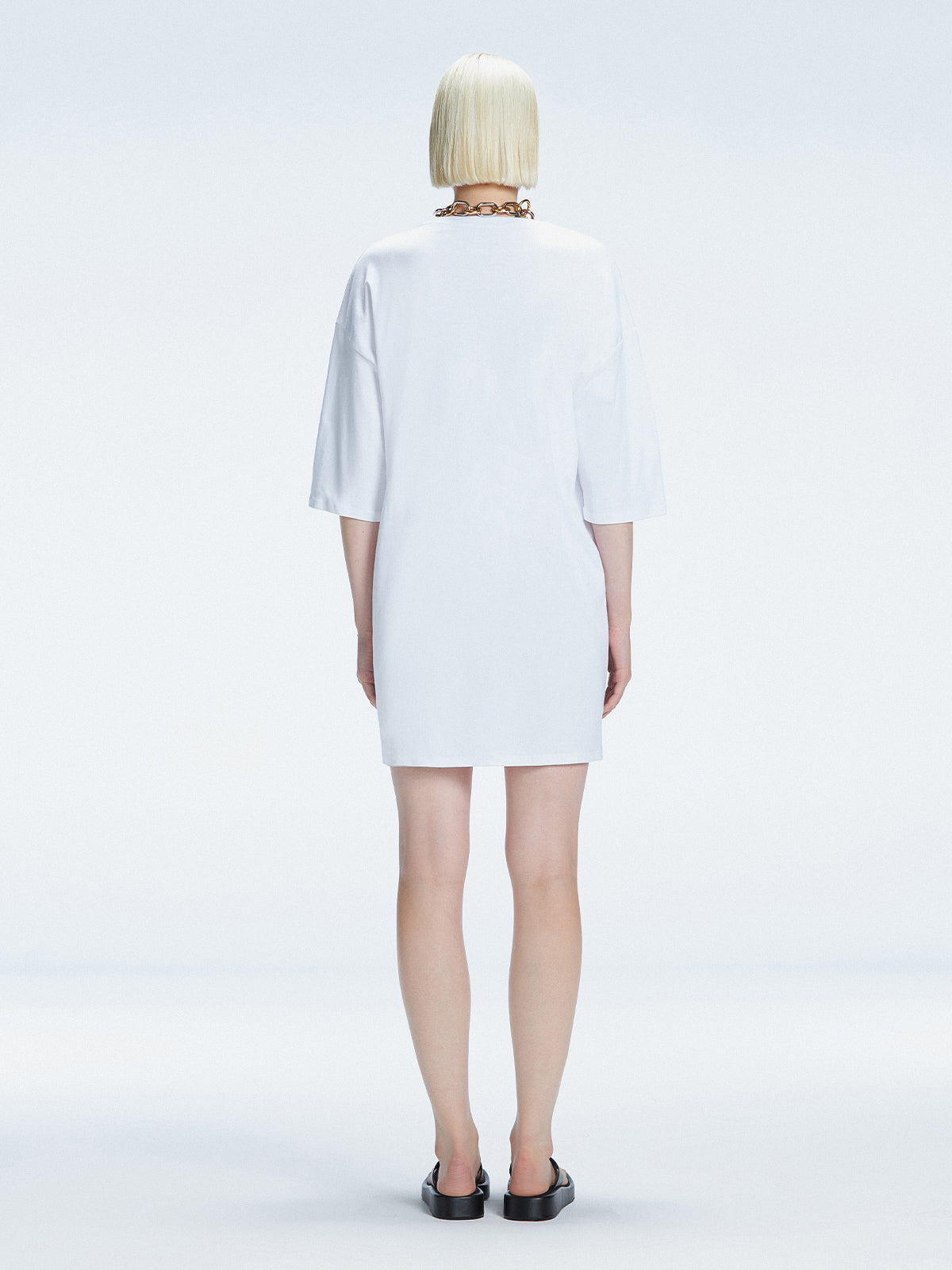 Back view of model wearing Lavinia White Mini Dress, highlighting the oversized design and comfortable fit.
