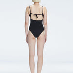 "Model turning to reveal the back of the Marigold Black Swimsuit, highlighting the adjustable straps and sleek fit."
