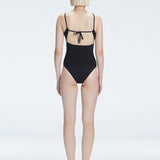 "Model turning to reveal the back of the Marigold Black Swimsuit, highlighting the adjustable straps and sleek fit."
