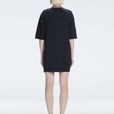 Back view of model wearing Lavinia Black Mini Dress, highlighting the oversized design and comfortable fit.
