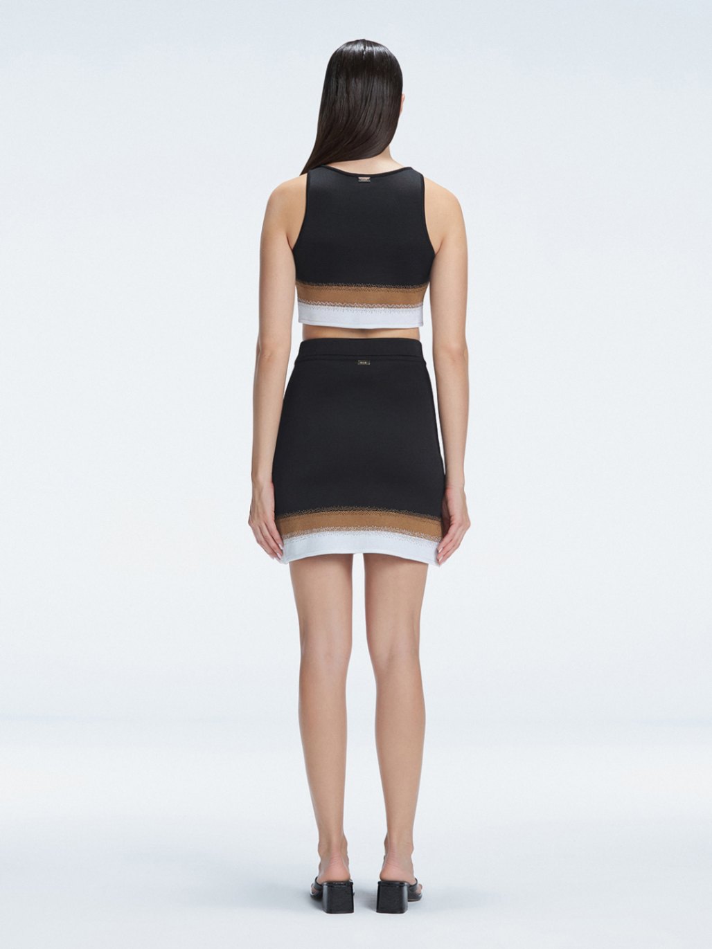 Back view  of the asymmetrical hemline of the Lydia Mini Skirt, illustrating its modern design.
