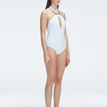 Side view of model showcasing the twist-front design and gold accessory on the Rosamund White One Piece swimsuit.
