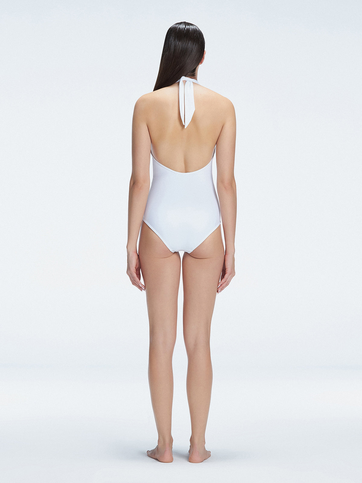 Back view of model wearing Rosamund White One Piece swimsuit, highlighting the low back and full bottom coverage.
