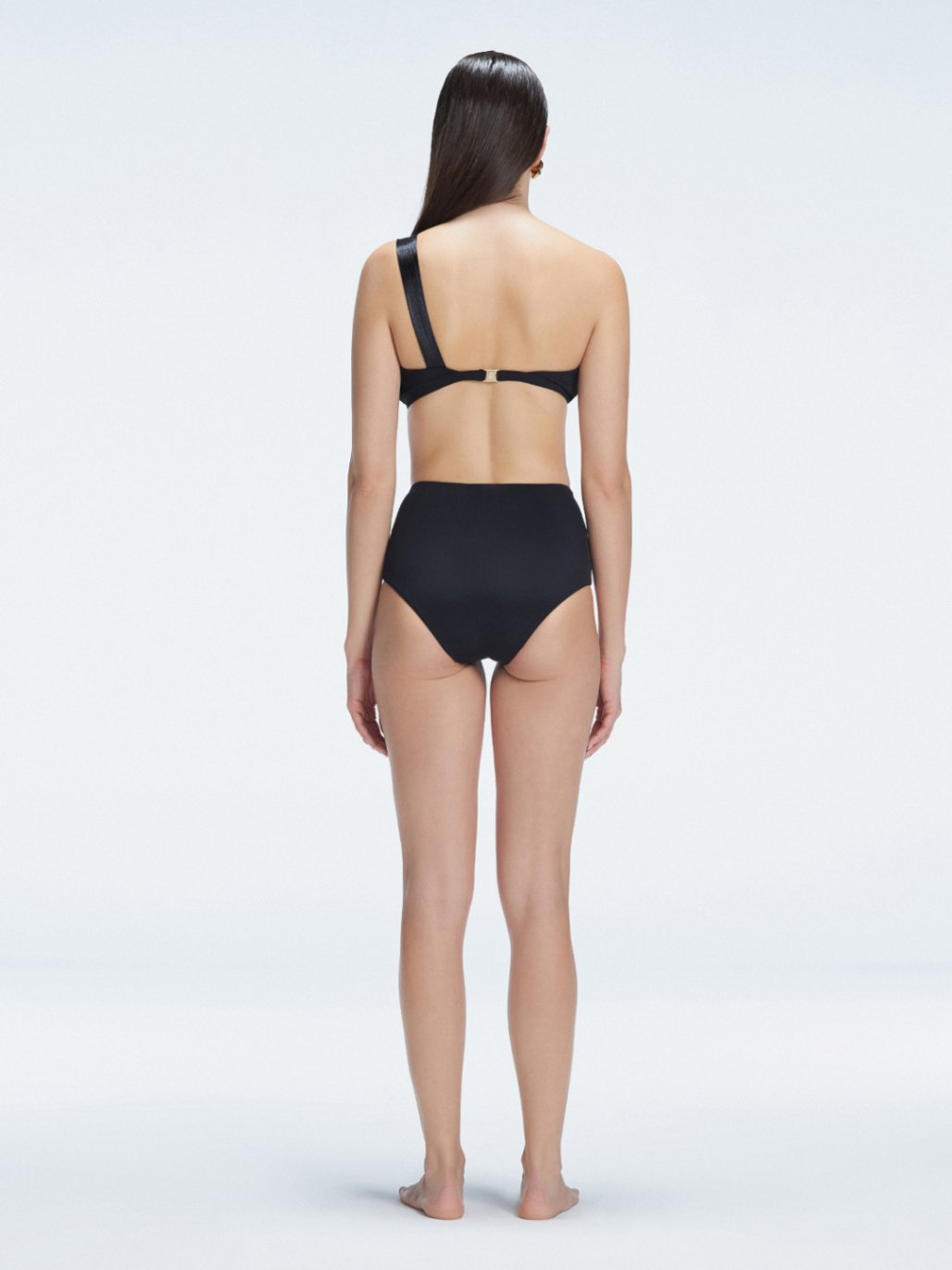 "Model showing the back of the Romina Black Bikini Bottom, highlighting the high-waist fit and sleek design."
