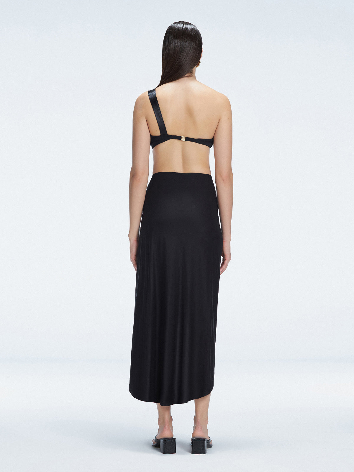 Back view of model wearing Gina Black Wrapped Skirt, highlighting the flowing silhouette and ankle-length design.
