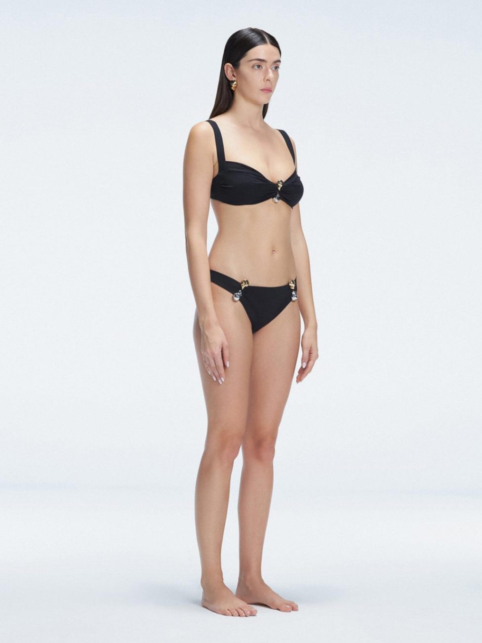 Side view of model showcasing the Emilia Black Bikini Set adjustable straps and bold buckle design.
