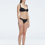 Side view of model showcasing the Emilia Black Bikini Top's adjustable straps and bold buckle design.
