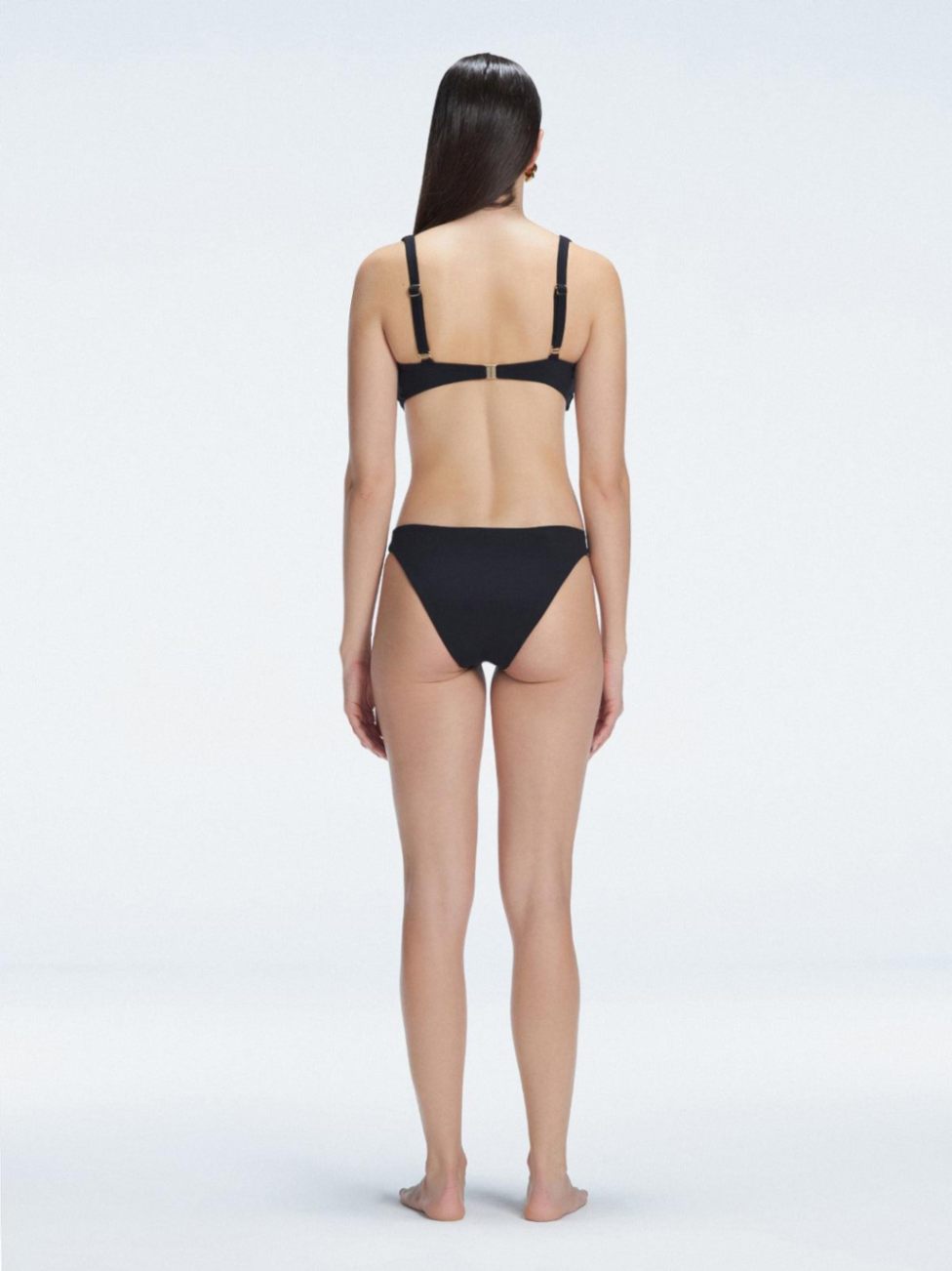 Back view of model wearing Emilia White Bikini Bottom, highlighting the moderate coverage and chic fit.
