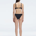 Back view of model wearing Emilia White Bikini Bottom, highlighting the moderate coverage and chic fit.

