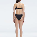 Back view of model wearing Emilia White Bikini Bottom, highlighting the moderate coverage and chic fit.
